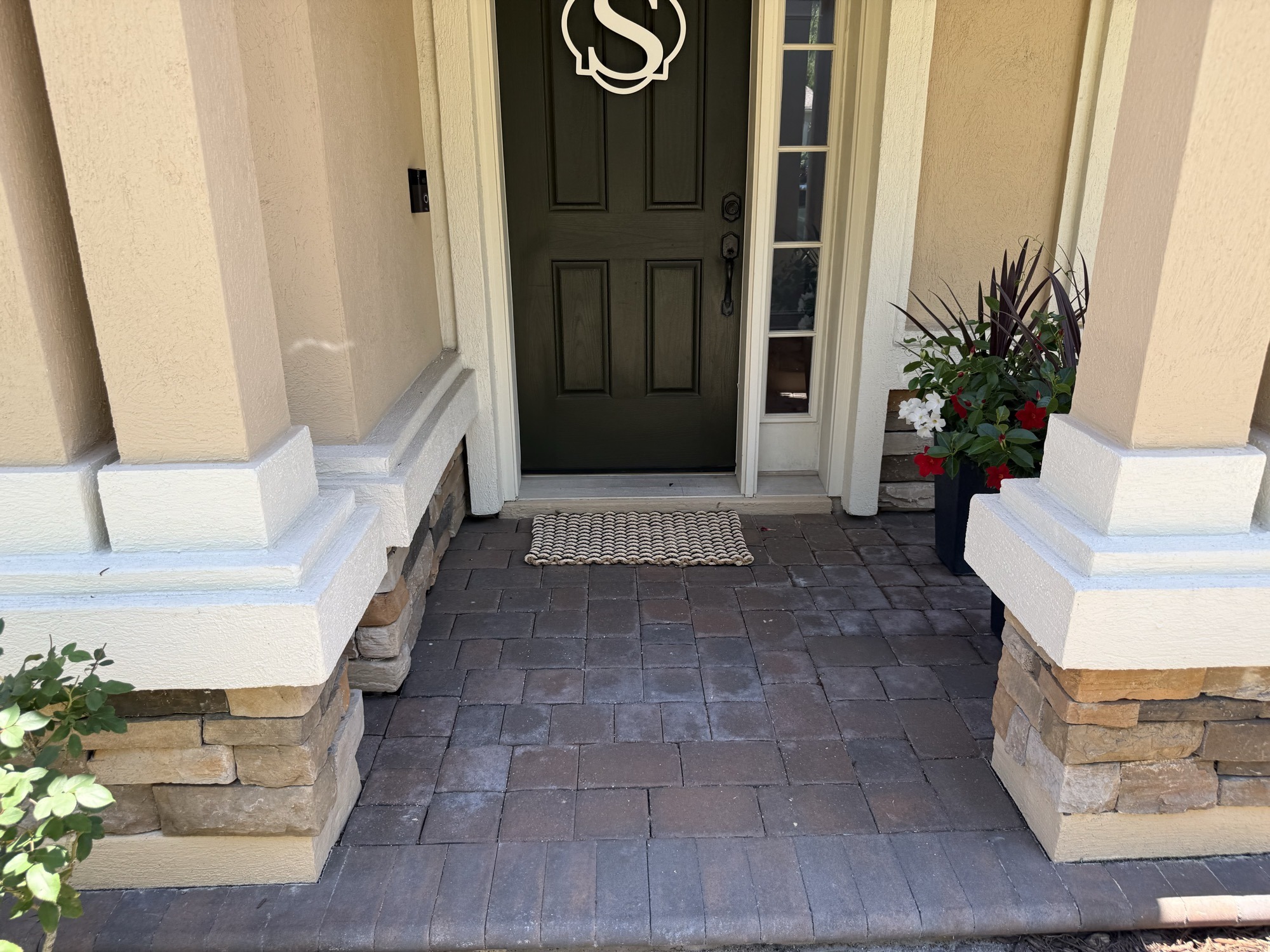 Front entry pavers with patchy, worn-off sealer at the highest-traffic spot on the property