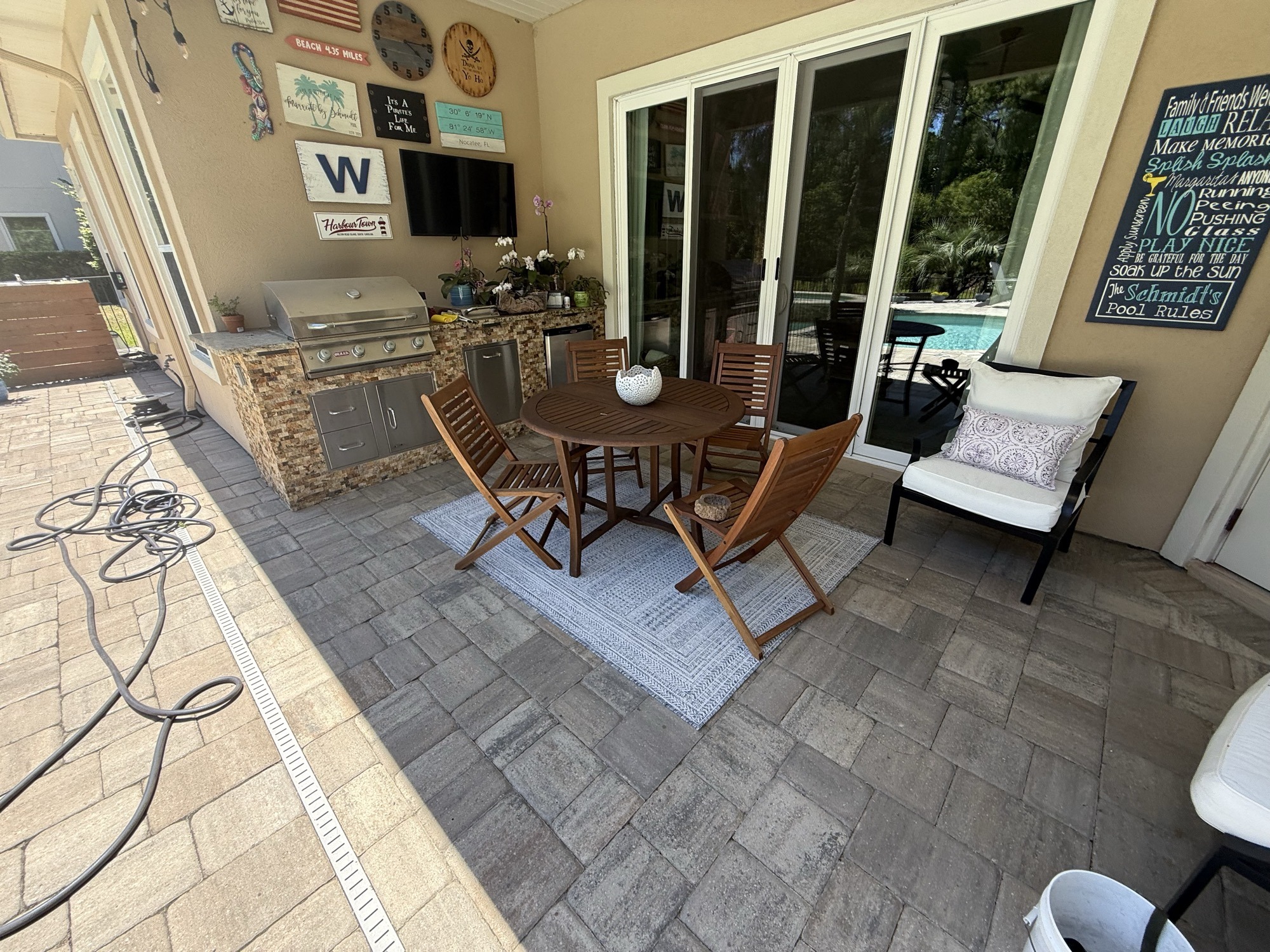 Back patio today &mdash; outdoor kitchen, dining set, hose still on the deck